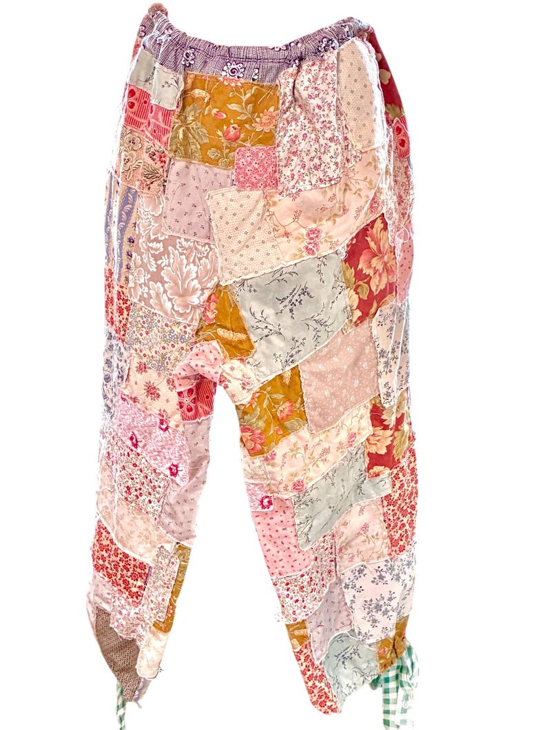 May include: Patchwork trousers in a variety of floral and patterned fabrics. The trousers feature a mix of pinks, reds, yellows, and greens, with a drawstring waist and gathered ankles. The patchwork design creates a unique, bohemian style.