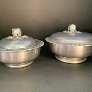 以下が含まれることがあります： ふた付きの銀製のサービングボウル2つ。ふたには装飾的な花の模様が施されています。ボウルにはビーズの縁取りがあります。