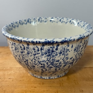 Peut inclure: Un bol en céramique rond présentant une base blanche avec un motif dense de taches bleues sur tout l'extérieur et le bord intérieur. Le bol a une forme incurvée lisse avec une large ouverture et une base légèrement effilée, finition uniforme.