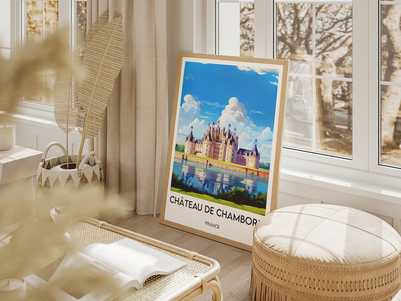 May include: A framed poster with a vintage travel illustration of Ch&acirc;teau de Chambord, a large French castle with a moat and reflection in the water. The poster has the text "Ch&acirc;teau de Chambord, France".