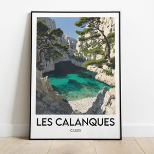 Peut inclure: Une affiche encadrée représentant Les Calanques de Cassis, en France. L'image montre une baie turquoise entourée de falaises blanches et d'arbres verts sous un ciel bleu clair. Les mots "LES CALANQUES" et "CASSIS" sont imprimés en bas.