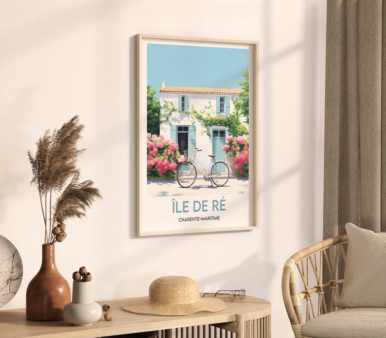 Op de afbeelding: Een ingelijste poster met een wit huis met blauwe luiken en een fiets ervoor. De poster heeft de tekst "&Icirc;le de R&eacute;" en "Charente-Maritime" erop.