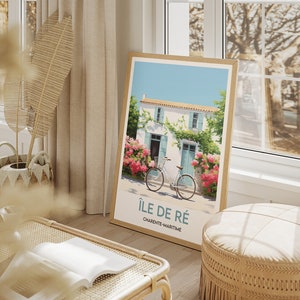 Op de afbeelding: Een ingelijste poster met een schilderij van een wit huis met blauwe luiken en een fiets ervoor. Het huis is omgeven door roze bloemen en groene wijnstokken. De poster heeft de tekst "&Icirc;le de R&eacute;" en "Charente-Maritime" erop.