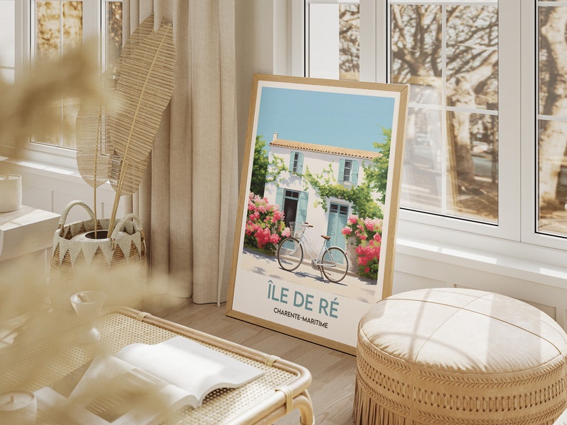 Op de afbeelding: Een ingelijste poster met een schilderij van een wit huis met blauwe luiken en een fiets ervoor. Het huis is omgeven door roze bloemen en groene wijnstokken. De poster heeft de tekst "&Icirc;le de R&eacute;" en "Charente-Maritime" erop.
