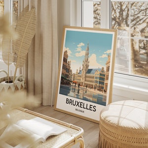 May include: A framed poster with a vintage illustration of the Grand Place in Brussels, Belgium. The poster has a white background with a blue sky and clouds. The text "BRUXELLES BELGIQUE" is printed at the bottom of the poster.