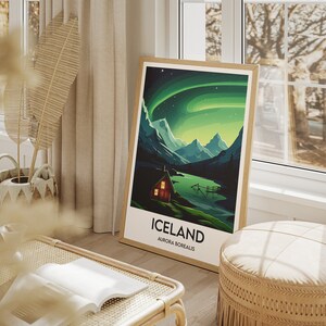 May include: A framed poster with a green and blue illustration of a mountain range with a small cabin in the foreground. The poster has the text "Iceland" and "Aurora Borealis" printed on it.