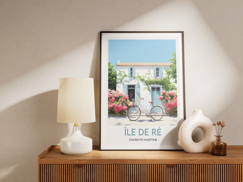 Op de afbeelding: Een ingelijste print van een wit huis met blauwe luiken en een fiets ervoor. Het huis is omgeven door roze bloemen en groene wijnstokken. De print is getiteld "&Icirc;le de R&eacute;, Charente-Maritime".