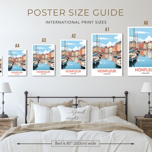 May include: A guide to poster sizes, showing different sizes of a poster with a colourful illustration of a harbour scene with boats and buildings. The poster is labelled "Honfleur, Normandy". The sizes are labelled A0, A1, A2, A3, A4, and A5. The poster is shown on a wall above a bed with a headboard and two bedside tables.