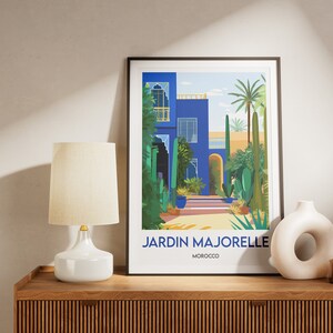 Pu&ograve; includere: Una stampa incorniciata di un edificio blu con un giardino di fronte. La stampa ha il testo "JARDIN MAJORELLE MAROCCO" in basso.