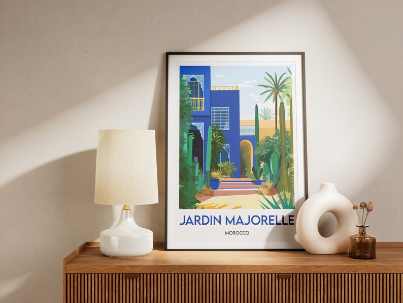 Pu&ograve; includere: Una stampa incorniciata di un edificio blu con un giardino di fronte. La stampa ha il testo "JARDIN MAJORELLE MAROCCO" in basso.