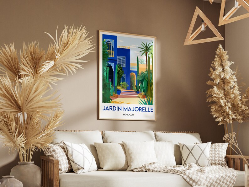 Pu&ograve; includere: Un poster incorniciato con un'illustrazione colorata di un edificio blu con un cortile e palme. Il testo "JARDIN MAJORELLE MAROCCO" &egrave; in fondo al poster.