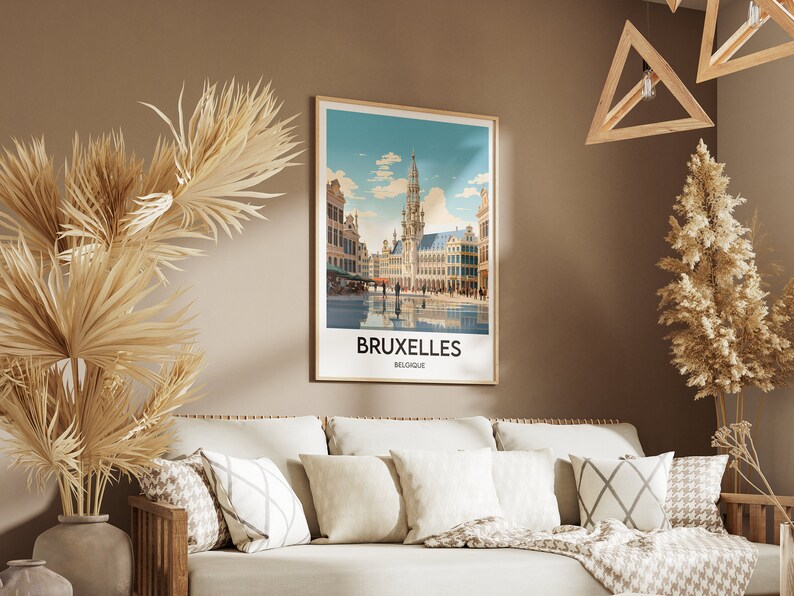 May include: A framed poster with a vintage travel illustration of the Grand Place in Brussels, Belgium. The poster has a white background with a blue sky and white clouds. The text "BRUXELLES BELGIQUE" is printed in black at the bottom of the poster.