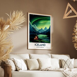 May include: A framed poster with a colorful illustration of a cabin in a mountain landscape with a lake and the aurora borealis in the sky. The poster has the text "Iceland" and "Aurora Borealis" printed on it.