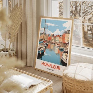 May include: A framed illustration of a harbour scene in Honfleur, Normandy, France. The illustration features colourful buildings lining a canal with boats docked along the water. The text "Honfleur, Normandie" is printed below the image.