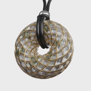 May include: A pendant necklace featuring a circular, open-center design. The pendant has a clear, geometric pattern with gold-colored metal accents. It hangs from a black, braided cord with a silver-colored clasp.