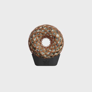 May include: A decorative sphere with a copper-colored lattice design, showcasing a central opening. The sphere rests on a black base with a star-like emblem. The sphere's interior appears to be filled with a mosaic of gray and white stones.