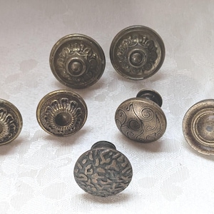 May include: An assortment of antique brass cabinet knobs. The knobs feature various designs, including floral patterns, textured surfaces, and a classic round shape. These decorative knobs are ideal for furniture restoration projects.