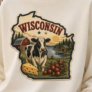 May include: A cream-colored crewneck sweatshirt featuring a large embroidered-style graphic of the state of Wisconsin. The design includes a black and white cow, a red barn, a wedge of Swiss cheese, red berries, and the text WISCONSIN.