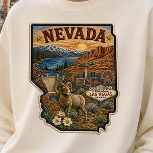 Può includere: Una felpa girocollo color crema con una grande e dettagliata toppa grafica dello stato del Nevada. Il design include un bighorn, flora desertica, la diga di Hoover, lo skyline di Las Vegas e il cartello Welcome to Fabulous Las Vegas.