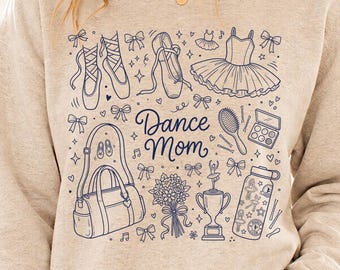 Op de afbeelding: Een lichtgrijs sweatshirt met een blauw grafisch ontwerp met balletschoenen, een tutu en de woorden "Dance Mom". Het ontwerp bevat ook een danstas, bloemen, een trofee en andere dansgerelateerde iconen. Het model draagt een blauwe spijkerbroek.