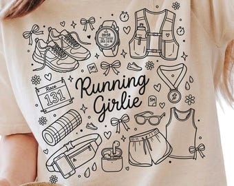 Op de afbeelding: Een beige t-shirt met een zwarte afbeelding van hardloopartikelen, waaronder schoenen, een horloge, een vest en een korte broek. De tekst "Running Girlie" is geschreven in een scriptlettertype. Een persoon houdt een beige mok vast.