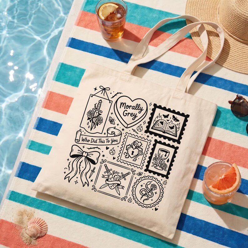 May include: Cream-colored tote bag with black graphic illustrations and text. The bag features a variety of designs, including a heart with the words "Morally Grey", a sword through a rose, and a bow. The text "Who Did This To You" is also present.