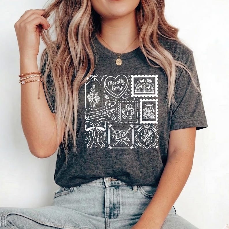 May include: Dark gray t-shirt with a white graphic design featuring various illustrations within stamp-like frames. The design includes a heart, a bow, a sword, and the text "Morally Grey" and "Who Did This To You".