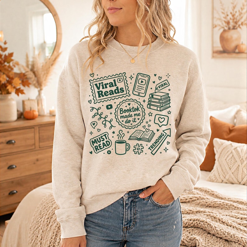 May include: A light gray sweatshirt with a green graphic design featuring the words "Viral Reads," "Booktok made me do it," and "Must Read." The design includes book stacks, a coffee mug, and a trending arrow.