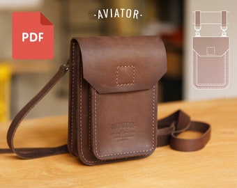 Puede incluir: Un bolso de cuero marrón cruzado con cierre de solapa y un pequeño bolsillo en la parte delantera. El bolso tiene una correa y el texto "AVIATOR" está estampado en la parte delantera.
