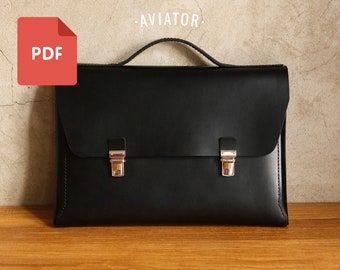 Puede incluir: Maletín de cuero negro con cierres plateados y un asa superior. La palabra "AVIATOR" está encima del maletín. Un icono PDF rojo está en la esquina superior izquierda. El maletín está sobre una superficie de madera.