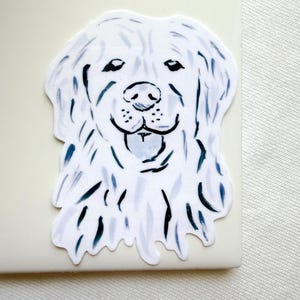 May include: A die-cut sticker featuring a stylized illustration of a golden retriever dog head. The artwork uses a white base with expressive, loose brushstrokes in shades of dark blue and light grey to define the fur, eyes, and nose.