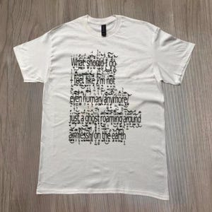 May include: White t-shirt with black text. The text reads "What should I do + feel like I'm not even human anymore! Just a ghost roaming around aimlessly on the earth."