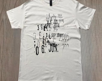 Könnte beinhalten: Weißes T-Shirt mit Rundhalsausschnitt und kurzen Ärmeln. Das Shirt hat einen verblassten schwarzen Aufdruck mit Daten und Zahlen. Die Daten beinhalten "APR 2014" und "JUN". Das Shirt ist aus einem weichen Material.