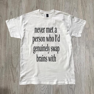 Puede incluir: Camiseta blanca con texto negro: "never met a person who I'd genuinely swap brains with". El texto está centrado. La camiseta tiene mangas cortas y cuello redondo.
