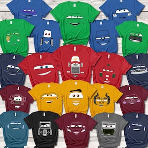 Puede incluir: Una colección de camisetas coloridas con diseños de coches de dibujos animados. Las camisetas están disponibles en varios colores, incluyendo azul, verde, rojo, amarillo, negro y granate. Cada camiseta muestra un diseño de cara de coche diferente.