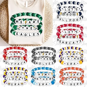 May include: A cream-colored t-shirt with a green beaded bracelet design that reads "WE ARE THE EAGLES". Below are several beaded bracelets in various colors, each with team names and phrases like "LET'S GO" and "IN MY ERA".