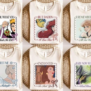 May include: Cream-coloured t-shirts featuring Disney character illustrations. Each shirt has a framed graphic and text, with phrases such as "Made Me Do," "I Love Him," and "All Too Well." The designs are in a cartoon style.