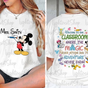 May include: White t-shirt with a Mickey Mouse graphic and the text "Mrs. Smith" on the front. The back of the shirt has a colorful graphic with the text "Welcome to our Classroom where the magic never stops and the adventure never ends!"