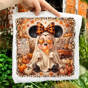May include: A white fabric square featuring a graphic of a cartoon mouse dressed as a ghost, wearing heart-shaped glasses and a plaid bow, blowing a bubble. The design includes pumpkins, an orange truck, and text reading HELLO FALL COZY DAYS WARM DRINKS AND GOOD VIBES, all framed by a leopard print border.