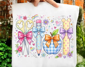 May include: A white tote bag featuring a colorful graphic print of school supplies including yellow scissors with a pink bow, a blue floral pencil with a light blue bow, a blue gingham apple with an orange bow, and a yellow polka dot ruler with a purple bow.