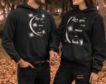May include: A couple wearing matching black hoodies with a white crescent moon and stars graphic. The text on the hoodies reads "Love you to the moon and back".