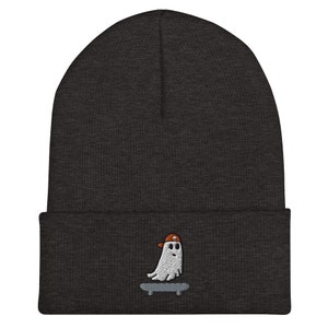 May include: A dark gray beanie with a white ghost wearing an orange hat and skateboarding embroidered on the front.