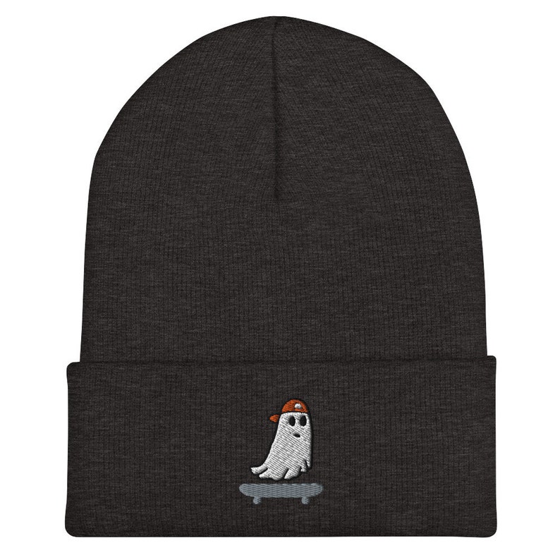 May include: A dark gray beanie with a white ghost wearing an orange hat and skateboarding embroidered on the front.