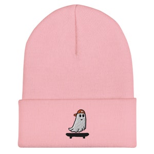May include: Pink beanie with an embroidered design of a ghost wearing a baseball cap and skateboarding.