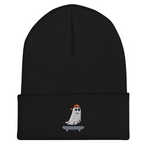 May include: Black beanie with a white embroidered ghost wearing a red and white baseball cap and skateboarding.