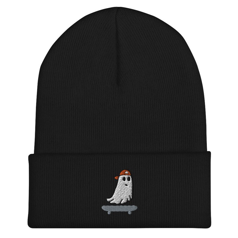 May include: Black beanie with a white embroidered ghost wearing a red and white baseball cap and skateboarding.