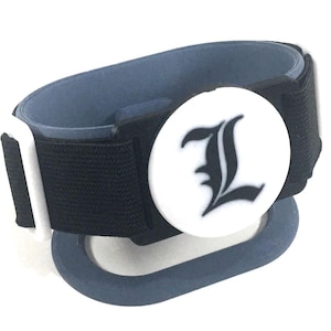 Puede incluir: Una taza de cerámica blanca con un asa negra y el texto "But First, Coffee" en negrita negra. La taza se encuentra sobre un fondo borroso, sugiriendo un ambiente acogedor.