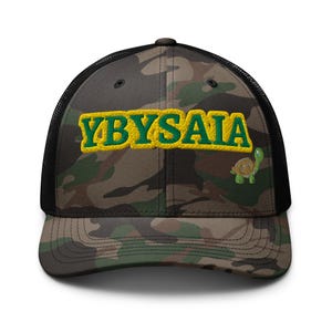 Puede incluir: Gorra de camionero de camuflaje con el texto bordado "YBYSAIA" en amarillo y verde. Una pequeña tortuga de dibujos animados está bordada en el lado derecho. La gorra tiene una parte trasera de malla negra y una visera curva.