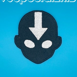 May include: A black embroidered patch featuring a stylized head silhouette with a white arrow pointing downward on the forehead and two white oval eyes. The text 96SpecialEMB is visible in white at the top of the image against a blue background.
