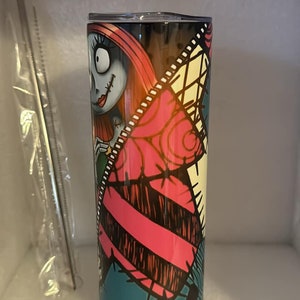 May include: A stainless steel tumbler with a colorful design featuring Sally from the Nightmare Before Christmas. The design includes pink, blue, black, and white colors.